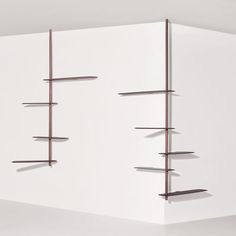 a white wall with some shelves on the side and one shelf in the middle that has several metal rods attached to it