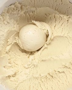 a white bowl filled with ice cream next to a wooden spoon