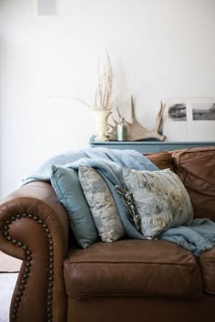 a brown leather couch with several pillows on it