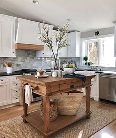 a kitchen with white cabinets and wooden island