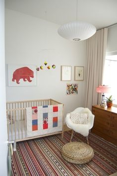 a baby's room with a crib, rocking chair and pictures on the wall