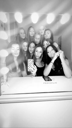 a group of women taking a selfie in front of a mirror with lights behind them