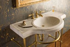 a white sink sitting under a mirror next to a gold faucet in a bathroom