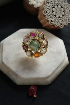 Skillfully made using classic methods, the ring features a fragile design embellished with semi-precious navrattan gemstones and the radiance of multicolored stones. These stones impart a touch of sophistication to this timeless treasure. Enhance your fashion with this exceptional ring. Closure - Adjustable Weight- 17gms Handcrafted in Jammu and Kashmir Paisley Pop travels the depths of India to learn techniques and crafts from deep down in the local markets and villages. We give utmost importance to our quality and packaging. Our goal is to ensure you receive exactly what you are looking for and for your experience to be special and memorable. We are ready to help and advise you through your purchase. IT' S  A W E S O M E * Our lovely packaging is designed by our co-founder Tanya. And all Luxury Elegant Meenakari Rings, Luxury Multicolor Rings With Center Stone, Elegant Multicolor Ruby Ring, Elegant Multicolor Rings, Elegant Multicolor Gemstones With Center Stone, Heirloom Multicolor Oval Jewelry, Multicolor Oval Heirloom Ring, Heirloom Style Multicolor Oval Rings, Heirloom Multicolor Oval Rings