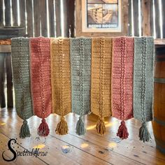 four crocheted tasselled curtains hanging on a wooden floor next to a barrel