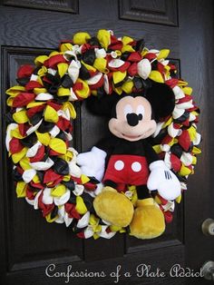 a mickey mouse wreath is hanging on a door with a stuffed animal in the middle