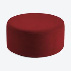 a red round ottoman sitting on top of a white floor