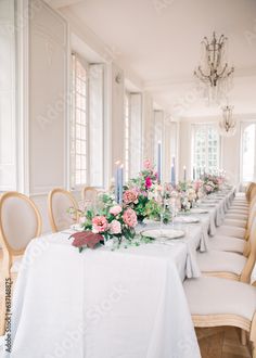 a long table is set with flowers and candles for a formal dinner or reception in an elegant setting