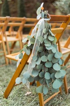 a bunch of chairs sitting in the grass with eucalyptus leaves tied to them and some ribbons hanging from them