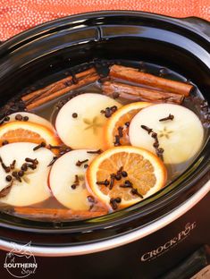 apples, oranges and cinnamon sticks are cooked in the crock pot