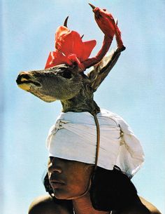 a woman wearing a hat with flowers on it's head in front of the ocean