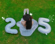 a woman sitting on the ground next to an inflatable number