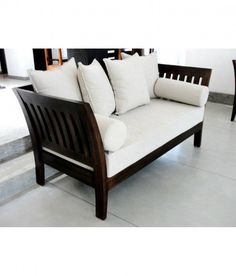 a white couch sitting on top of a tiled floor next to a wooden table and chair