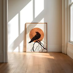 a black bird sitting on top of a tree branch in front of an orange moon