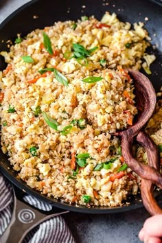 a pan filled with rice and vegetables on top of a table next to utensils