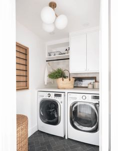 a washer and dryer in a small laundry room with white cabinets, black tile floor