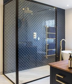 a bathroom with a stand up shower next to a white sink and wooden counter top