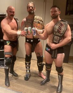 three men standing next to each other in wrestling gear