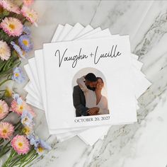 a couple is hugging on their wedding day with flowers in the foreground and napkins around them