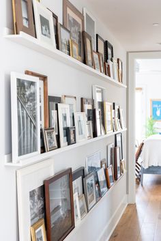 a wall filled with lots of framed pictures next to a dining room table and chairs