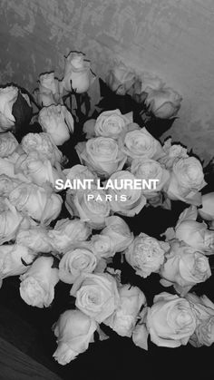 black and white photograph of flowers in front of a wall with the words saint laurent paris