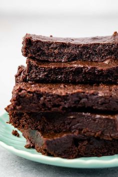 a stack of brownies sitting on top of a green plate