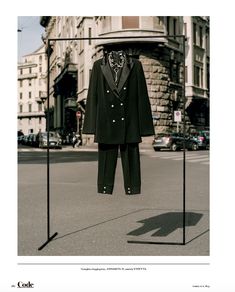 a black suit and tie hanging from clothes racks in the middle of a city street