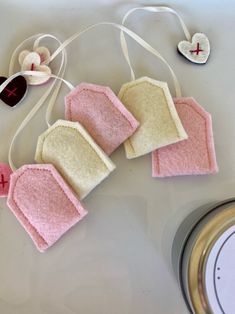 three pieces of pink and white felt hanging from a string on top of a table