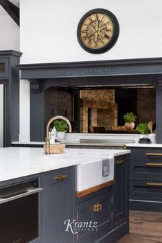 a large clock mounted to the side of a wall above a kitchen sink and oven