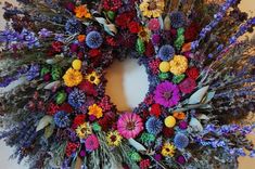 a wreath made out of dried flowers on a white surface with purple, yellow and orange colors