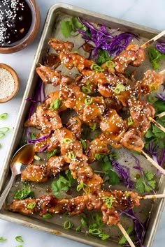 chicken skewers with sesame seeds and purple cabbage sprouts on a baking sheet