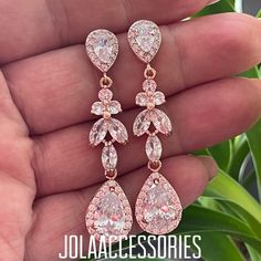 a pair of pink and white cubicge earrings in the palm of someone's hand