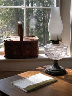 a lamp sitting on top of a wooden table next to a bag and window sill