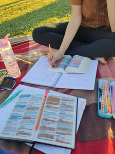 a woman is sitting on the ground with her notebooks and pens in front of her