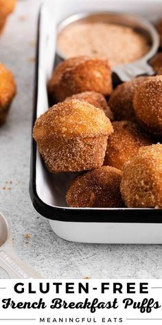 a tray filled with sugar covered doughnuts next to dipping sauce on the side