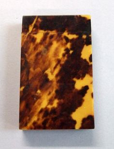 a brown and yellow marbled lighter on a white surface with a black dot in the middle