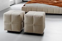 two foot stools sitting next to each other on the floor in front of a bed