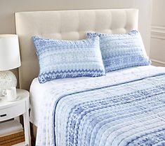 a bed with blue and white bedspread in a bedroom