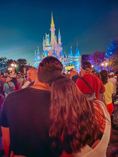 people standing in front of a castle at night with their backs turned to the camera