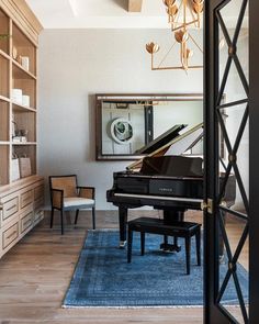 a living room filled with furniture and a grand piano in front of a large mirror