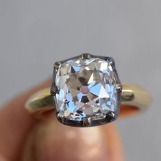 a close up of a person's hand holding an engagement ring with a diamond in it