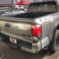 the back end of a silver truck parked in a parking lot next to other cars