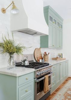 a kitchen with green cabinets and an oven in the center, along with a rug on the floor