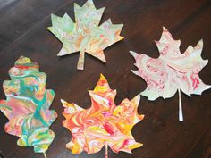 four different colored paper leaves sitting on top of a wooden table