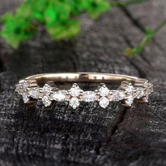 an image of a wedding ring with diamonds on it's side and green leaves in the background