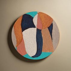 a circular painting with different colors and shapes on the wall above it is an orange, white, blue, and pink circle