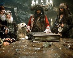 a group of pirates standing around a table with a dog in front of them and an old book on the table