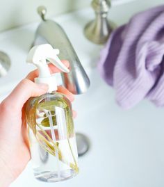 a person is holding a spray bottle in front of a sink