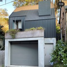 a garage with plants growing on the top of it's roof and doors open