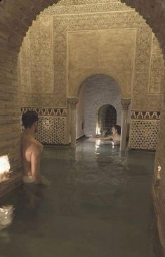 a man is sitting in the middle of an indoor swimming pool with no clothes on